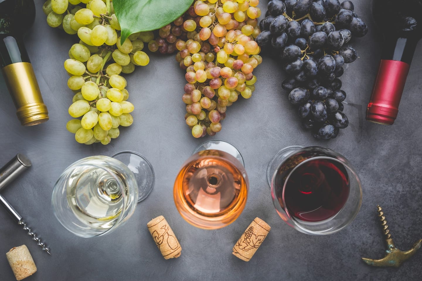 Verres de vin blanc, rosé et rouge et grappes de raisin