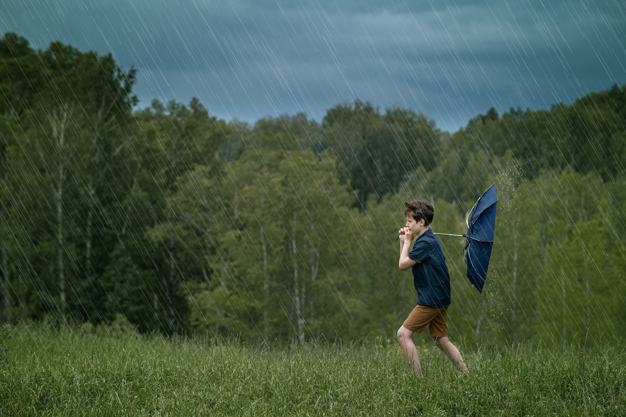 Teenager boy walking in the rain and strong wind. Weather