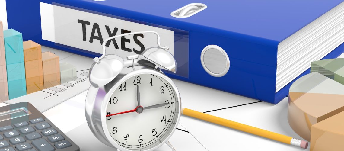 Clock with"Taxes" folder on busy office desk.
