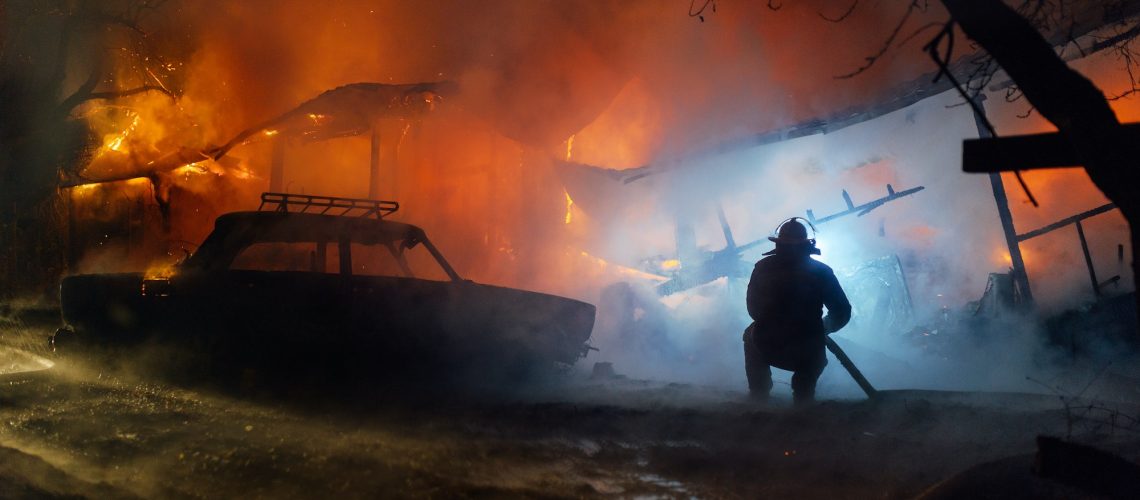 Firefighter putting out the fire of the house and car