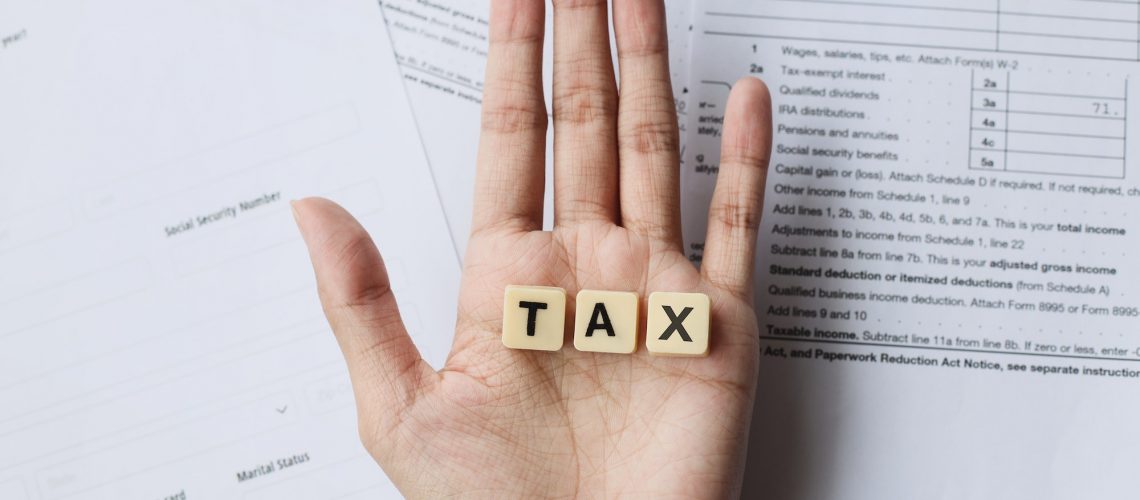 TAX words on palm hands against the tax forms.